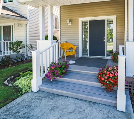 Door steps and concrete pathway leading to residential house main entrance under the porch