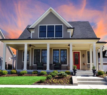 Sunset behind a Single-Family Suburban Craftsman House with Big Front Porch, White Pillars, and a Red Front Door.