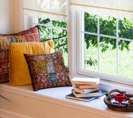 Cup of Coffee on a Tray, Piled Books and Square Pillows at the Reading Corner Inside the House.